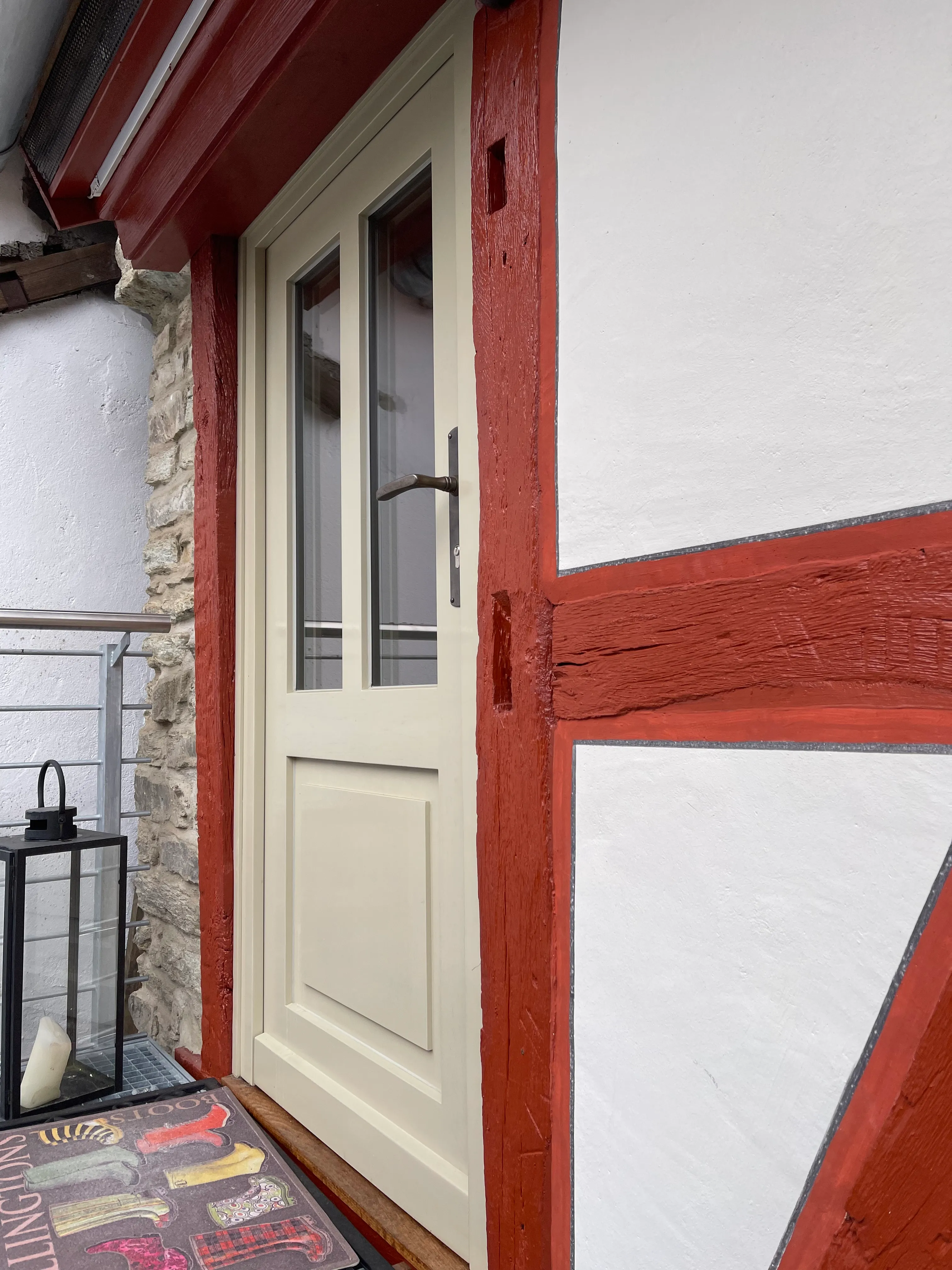 Detail der Fachwerkfassade mit roten Holzbalken und weißem Putz