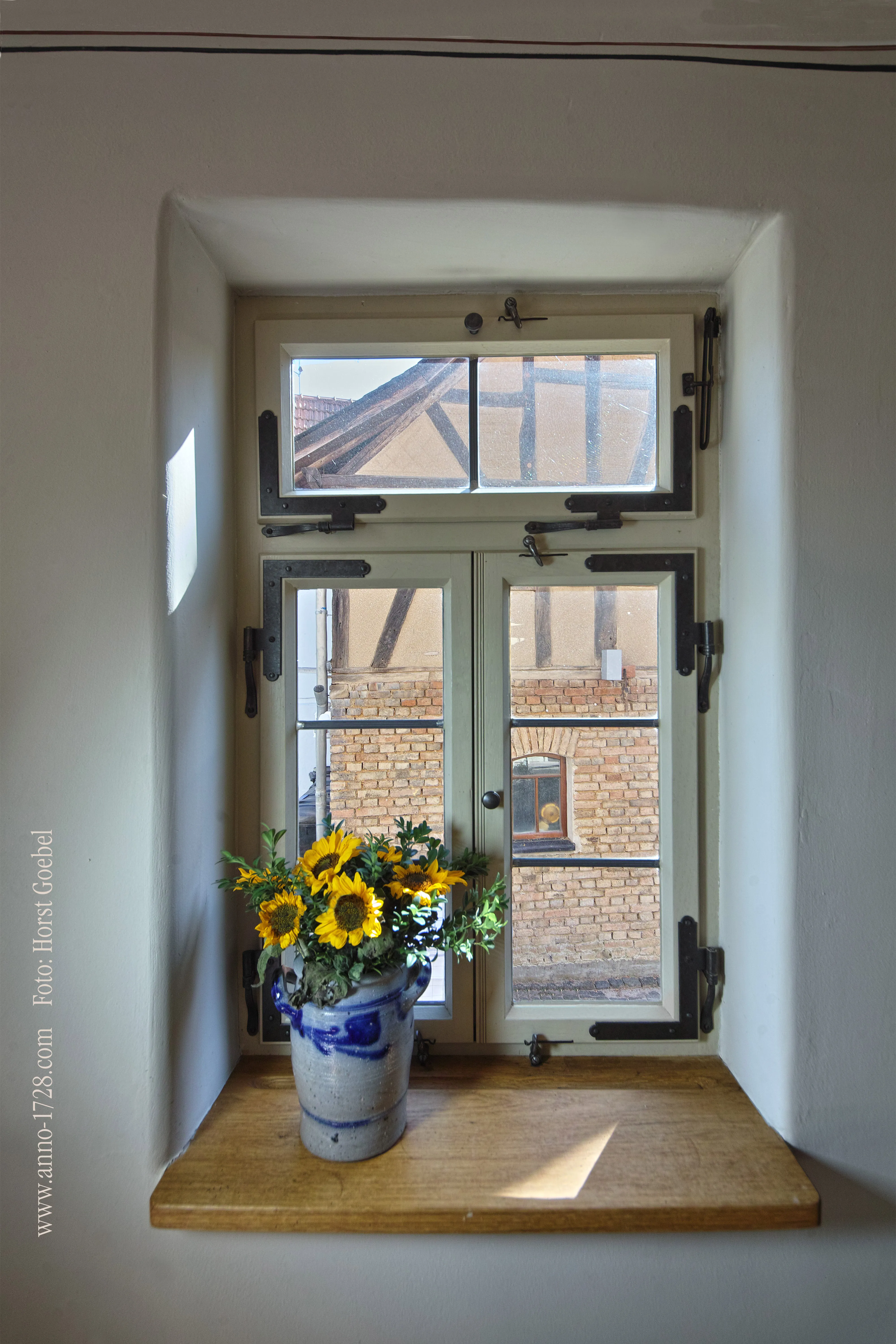 Fenster mit Sonnenblumen in traditioneller Steinzeugvase