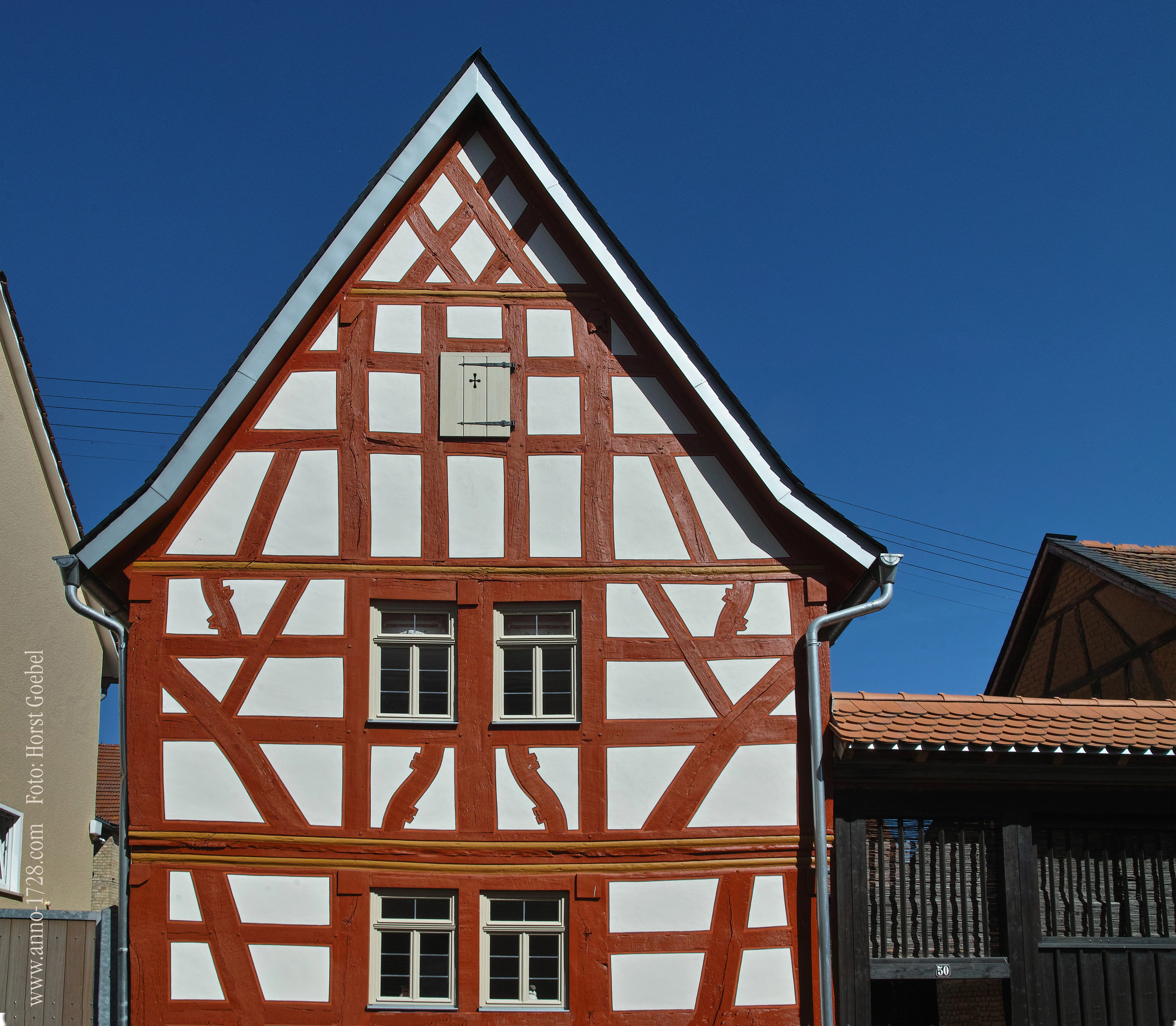 Preisgekrönte Fachwerkfassade mit rotem Gebälk und weißem Putz