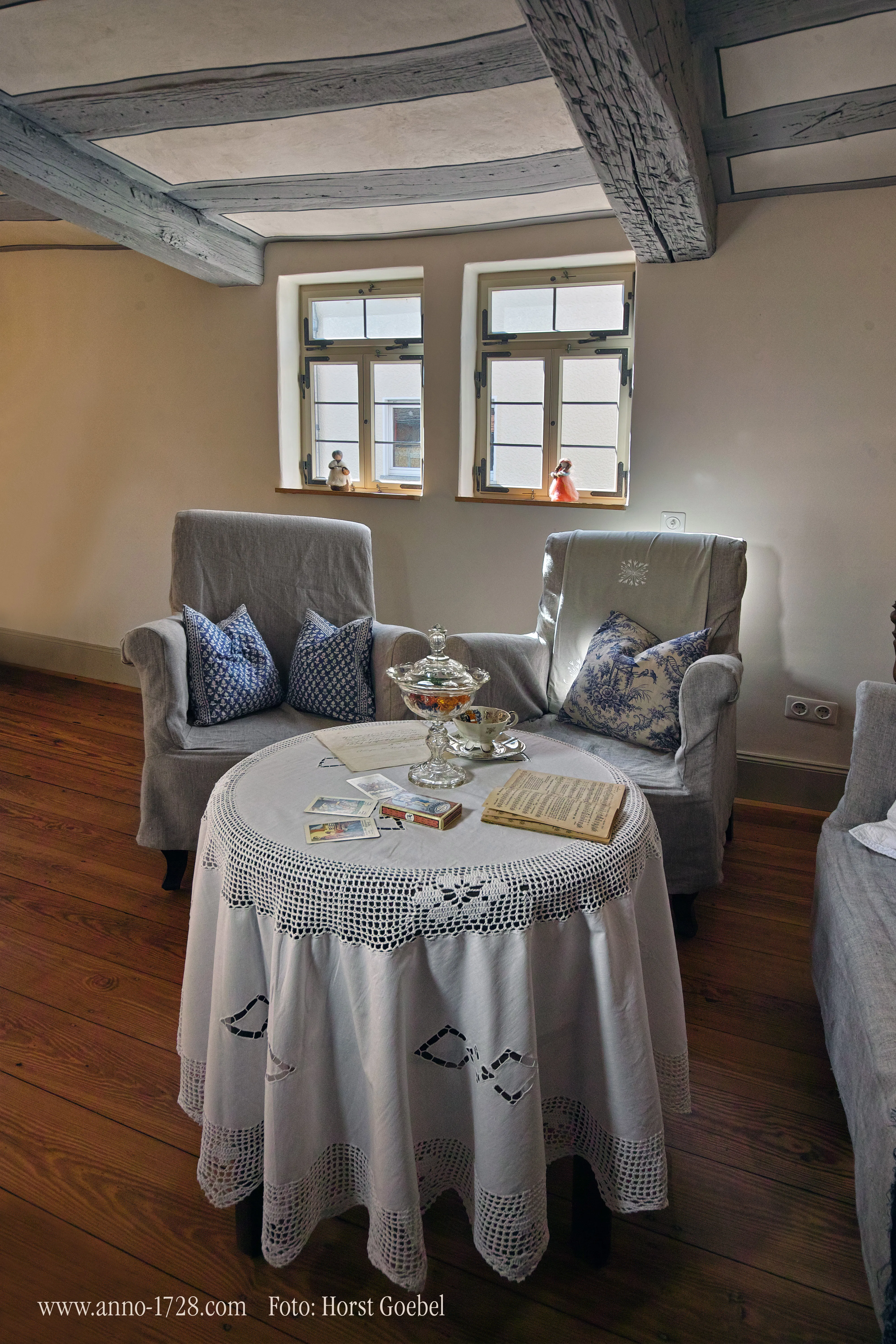 Gemütliche Sitzecke mit Sesseln und rundem Tisch unter Deckenbalken