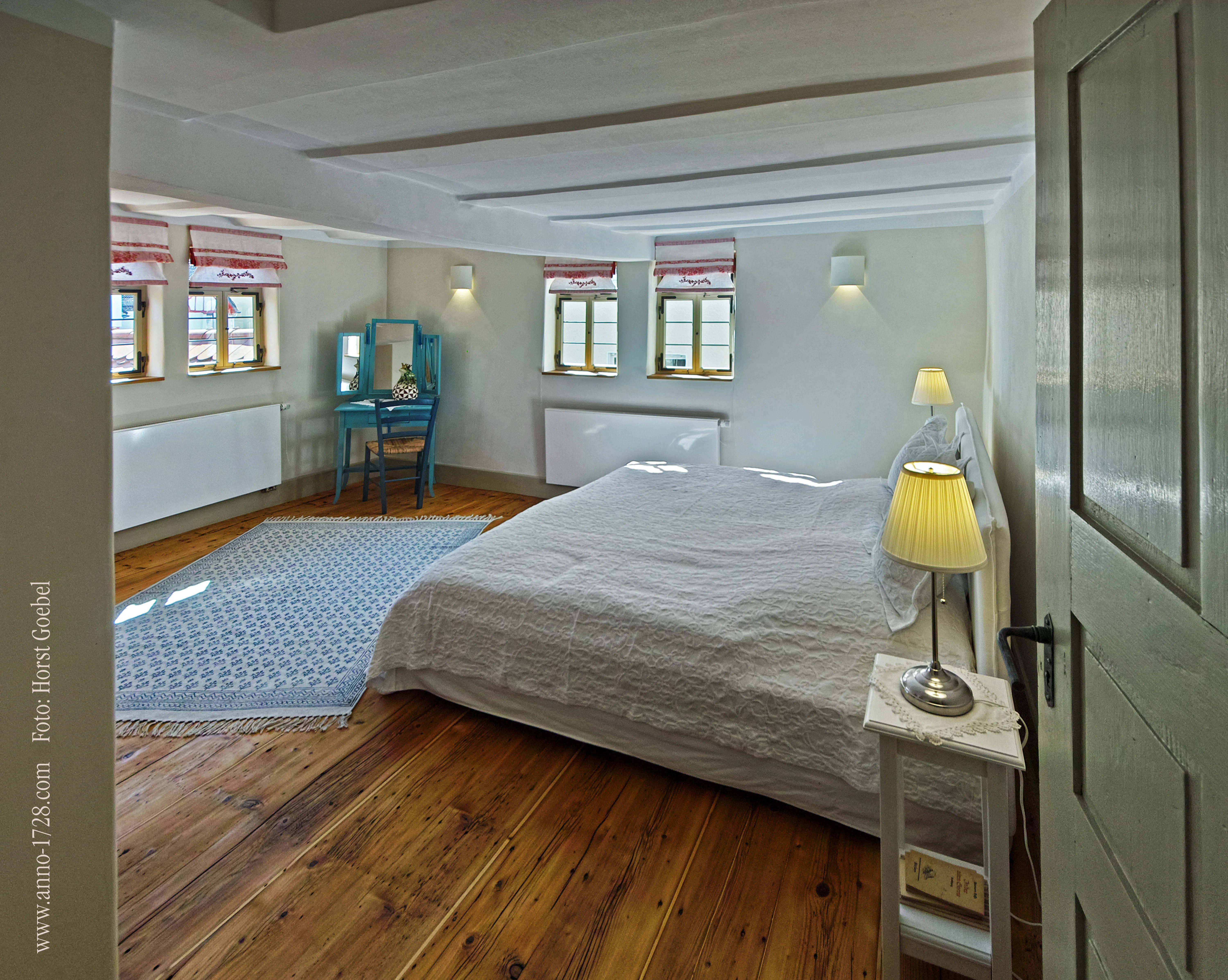 Großes Schlafzimmer mit Doppelbett, Holzdielen und Schminktisch