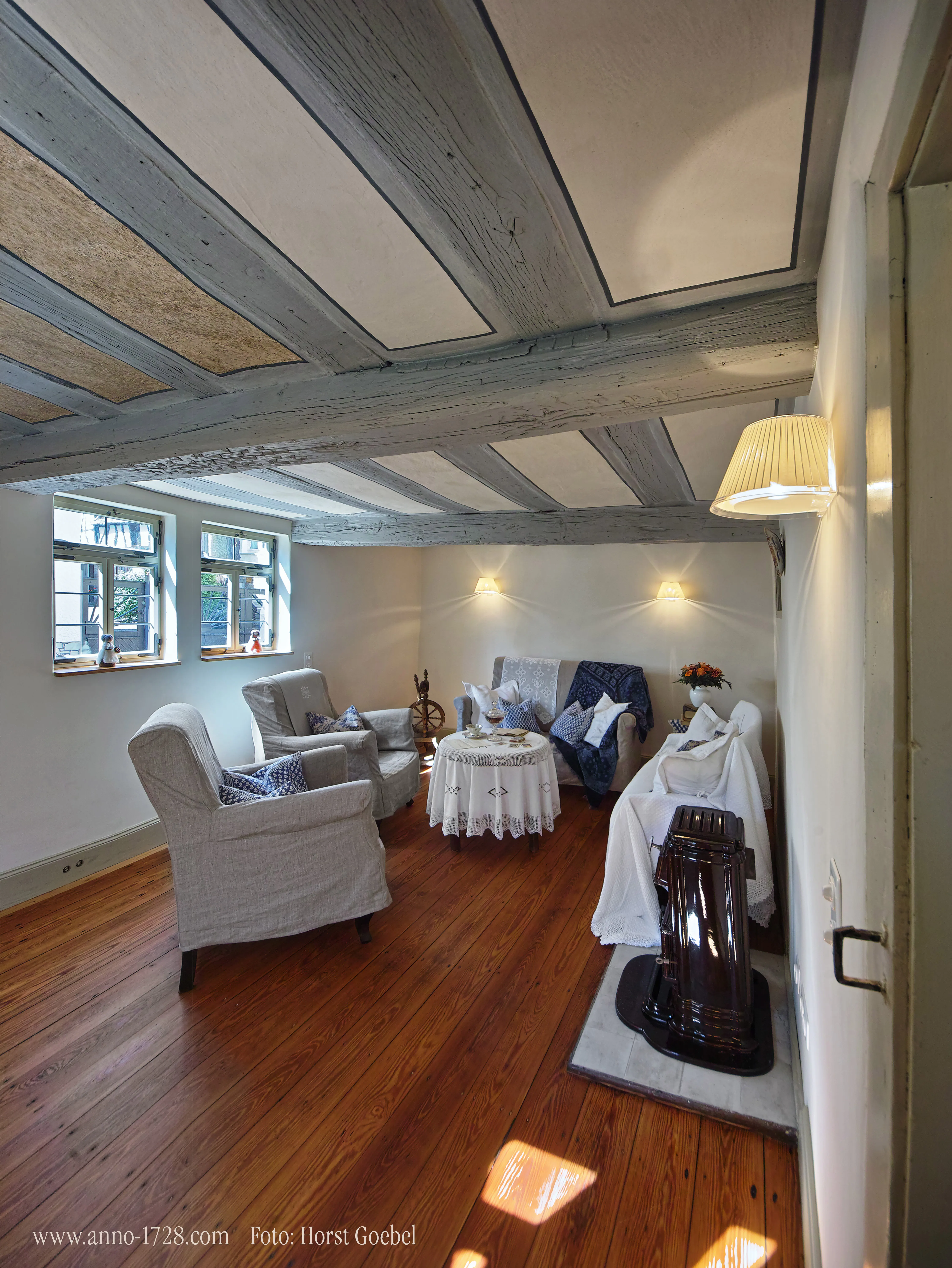 Wohnzimmer mit weißen Deckenbalken und historischem Kaminofen